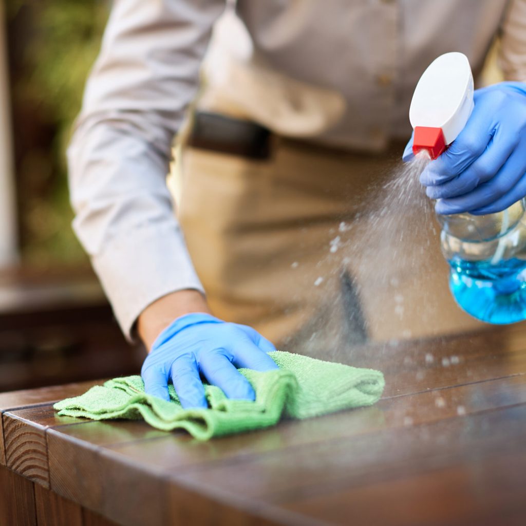 Close-up of waitress cleaning tables with disinfectant due to coronavirus epidemic.