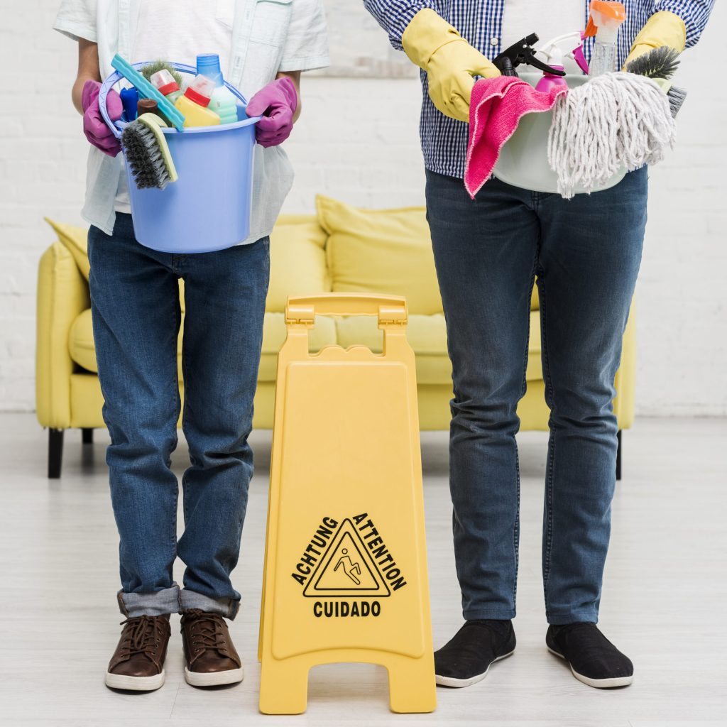 man-boy-holding-bucket-with-products-front-wet-floor-sign